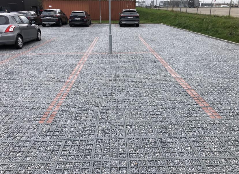 Parkeringsplads med grus og biler parkeret
