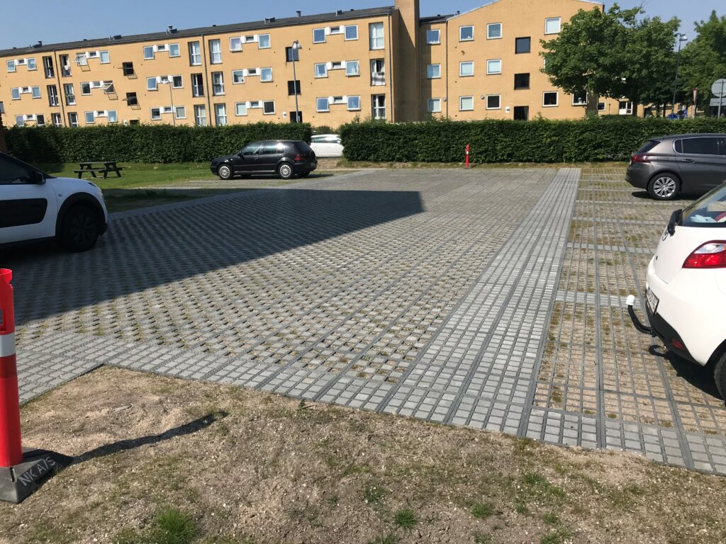 Parkeringsplads foran lejlighedsbygning på solrig dag