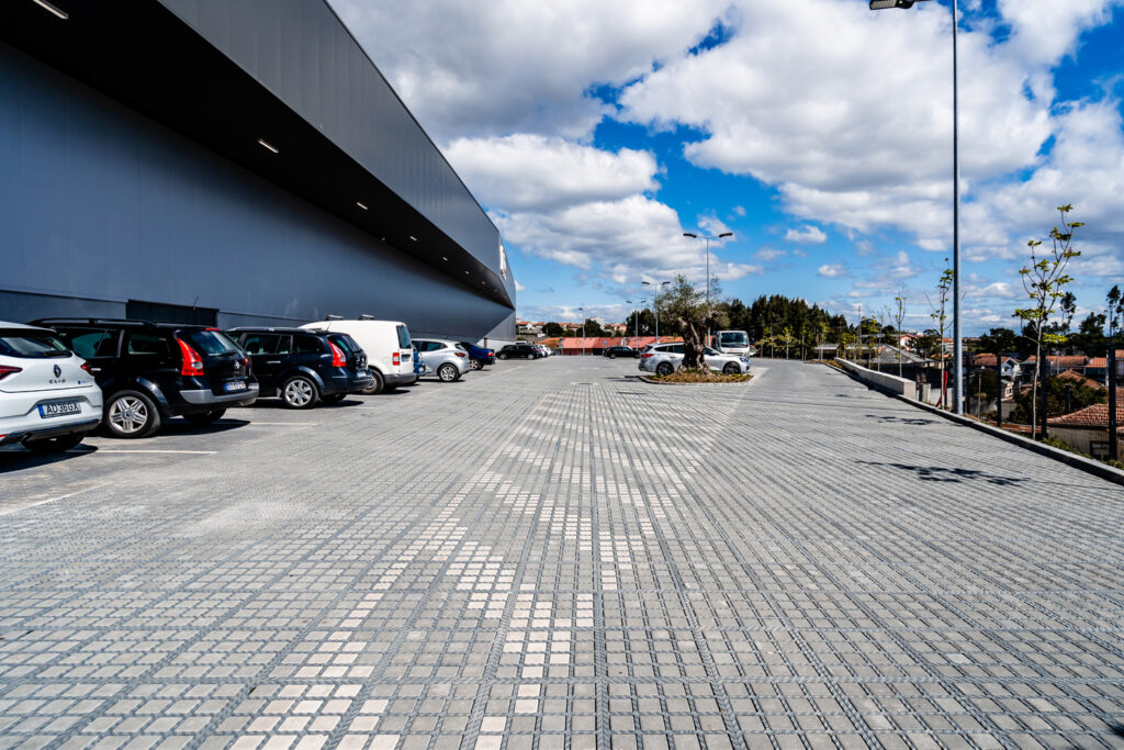 Parkeringsplads med biler ved moderne bygning